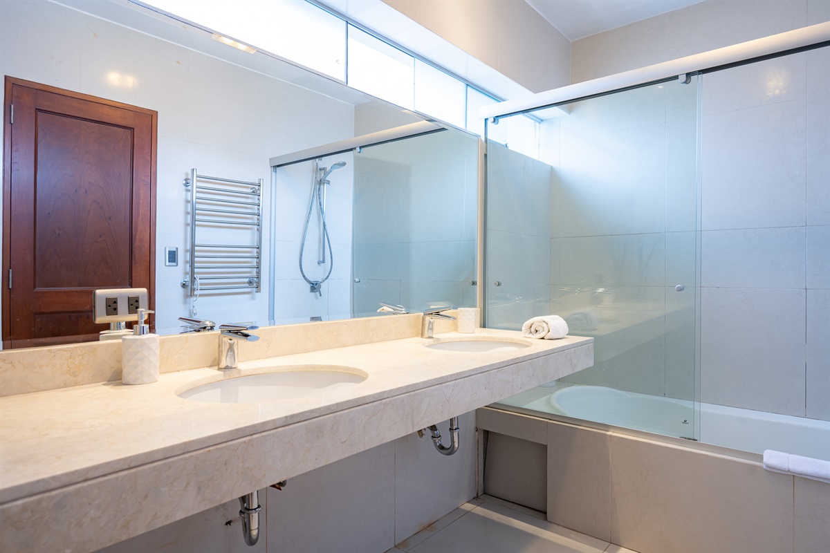 En-suite master bathroom with shower, towels, and complimentary toiletries  /  Baño en suite del dormitorio principal con ducha, toallas y artículos de tocador de cortesía