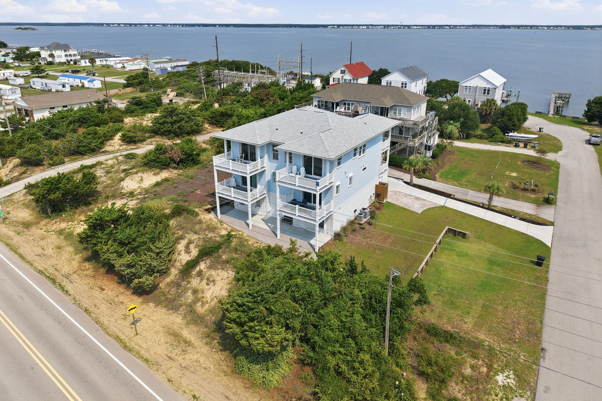 Elevated coastal view highlighting the home&rsquo;s spacious lot, multiple decks, and peaceful waterfront neighborhood setting