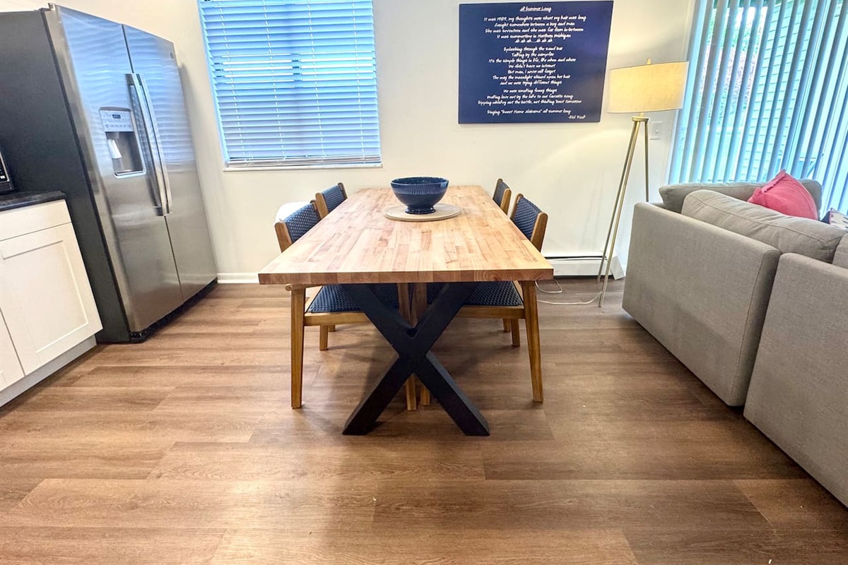 Modern kitchen with stainless steel appliances, open shelving, and a large butcher block dining table. Fully equipped for cooking, dining, and gathering. Bright, stylish, and functional—perfect for shared meals and memories