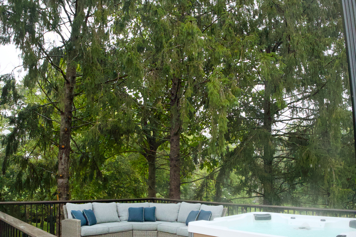 A deck equipped with privacy, a hot tub, lighting, and a comfy place to sit