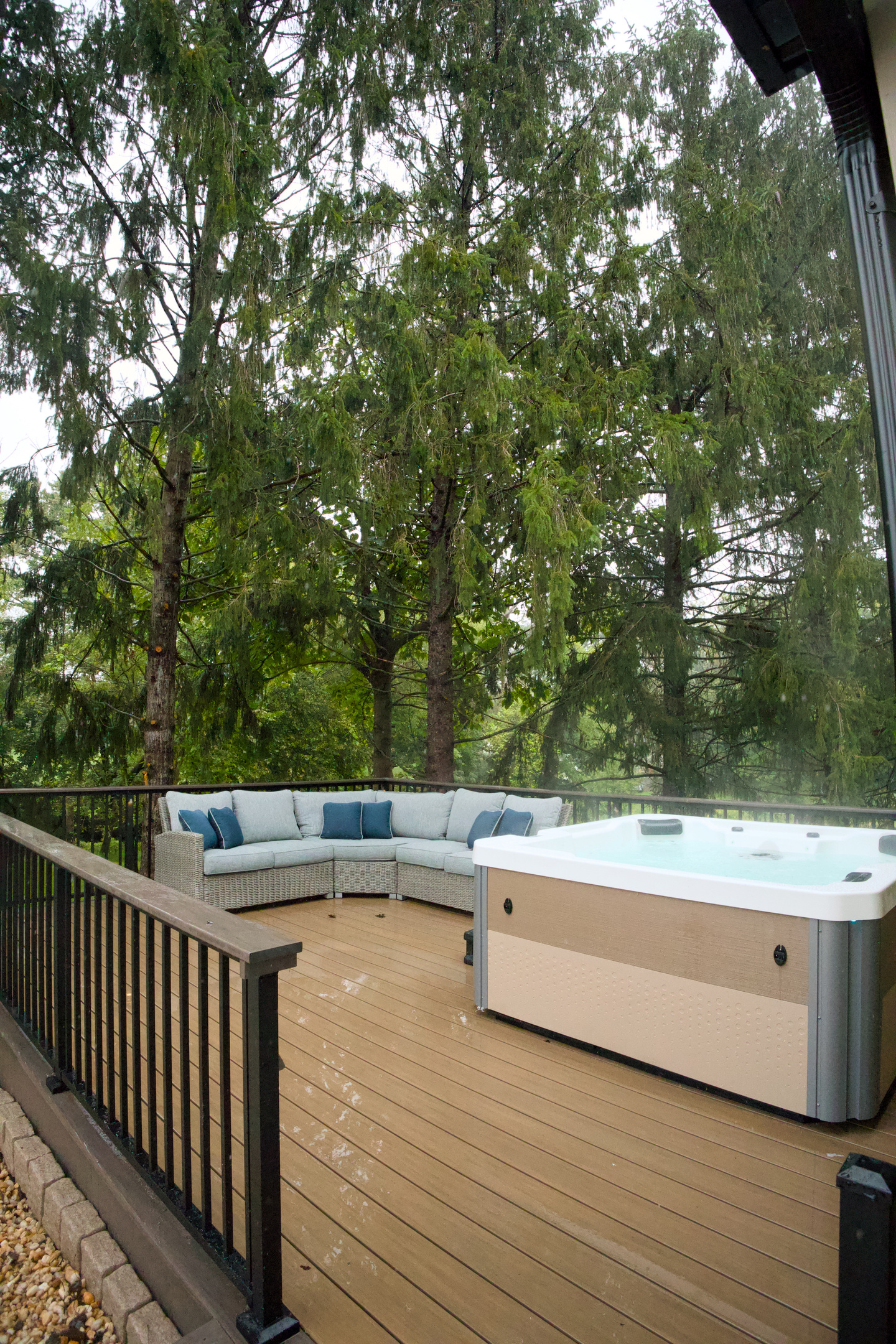 A deck equipped with privacy, a hot tub, lighting, and a comfy place to sit