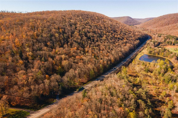 This drone view captures the serene setting—surrounded by forested hills, just off scenic Route 6, and moments from hiking, biking, and stargazing adventures. Your private escape starts here.