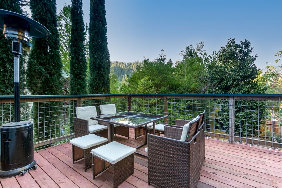 - Elevated deck with cushioned wicker seating and glass top table for outdoor dining  
- Surrounded by beautiful greenery and tall trees for privacy and scenic views  
- Outdoor heater ensures comfort for relaxing evenings year round  
