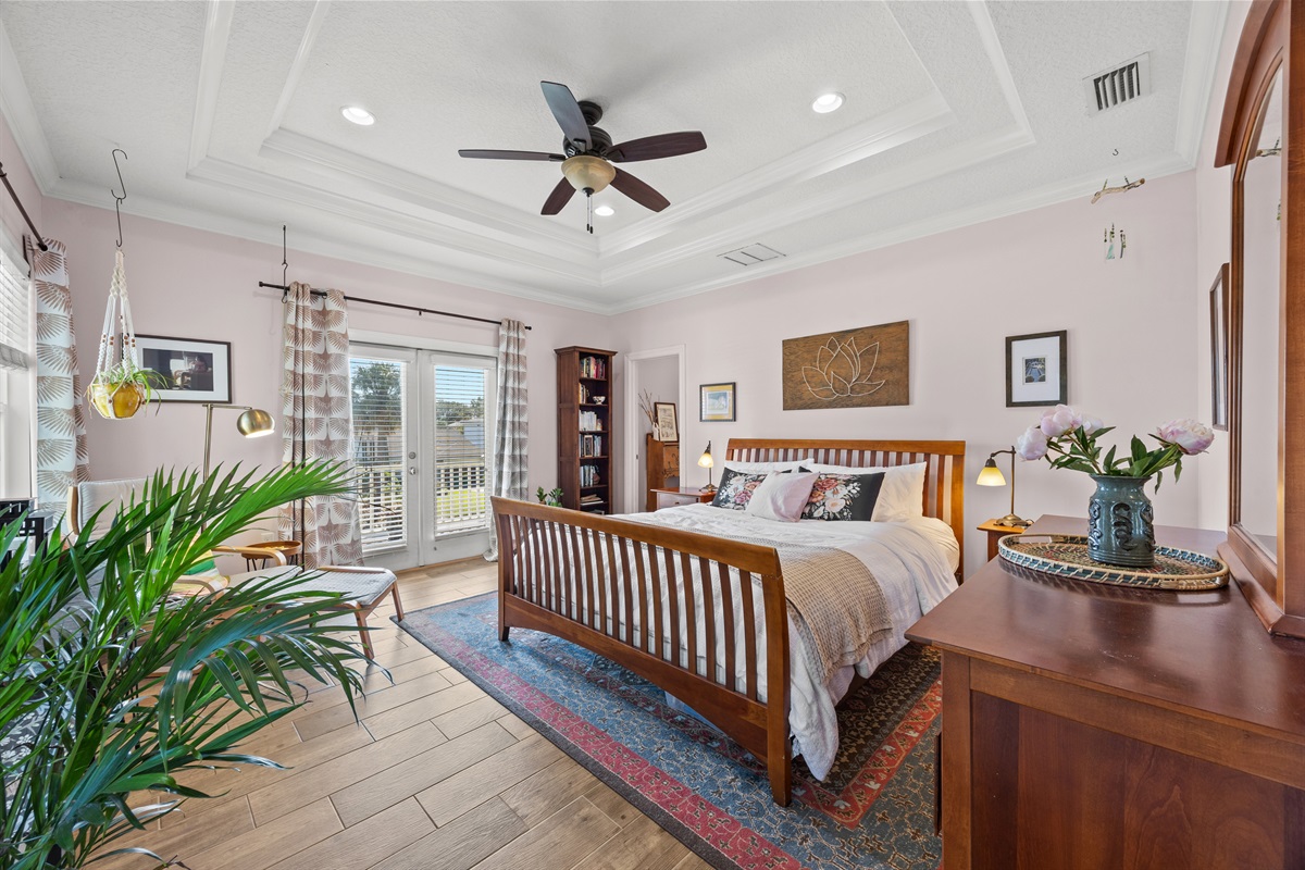 A spacious and modern primary bedroom filled with plenty of natural light and a breezy balcony.