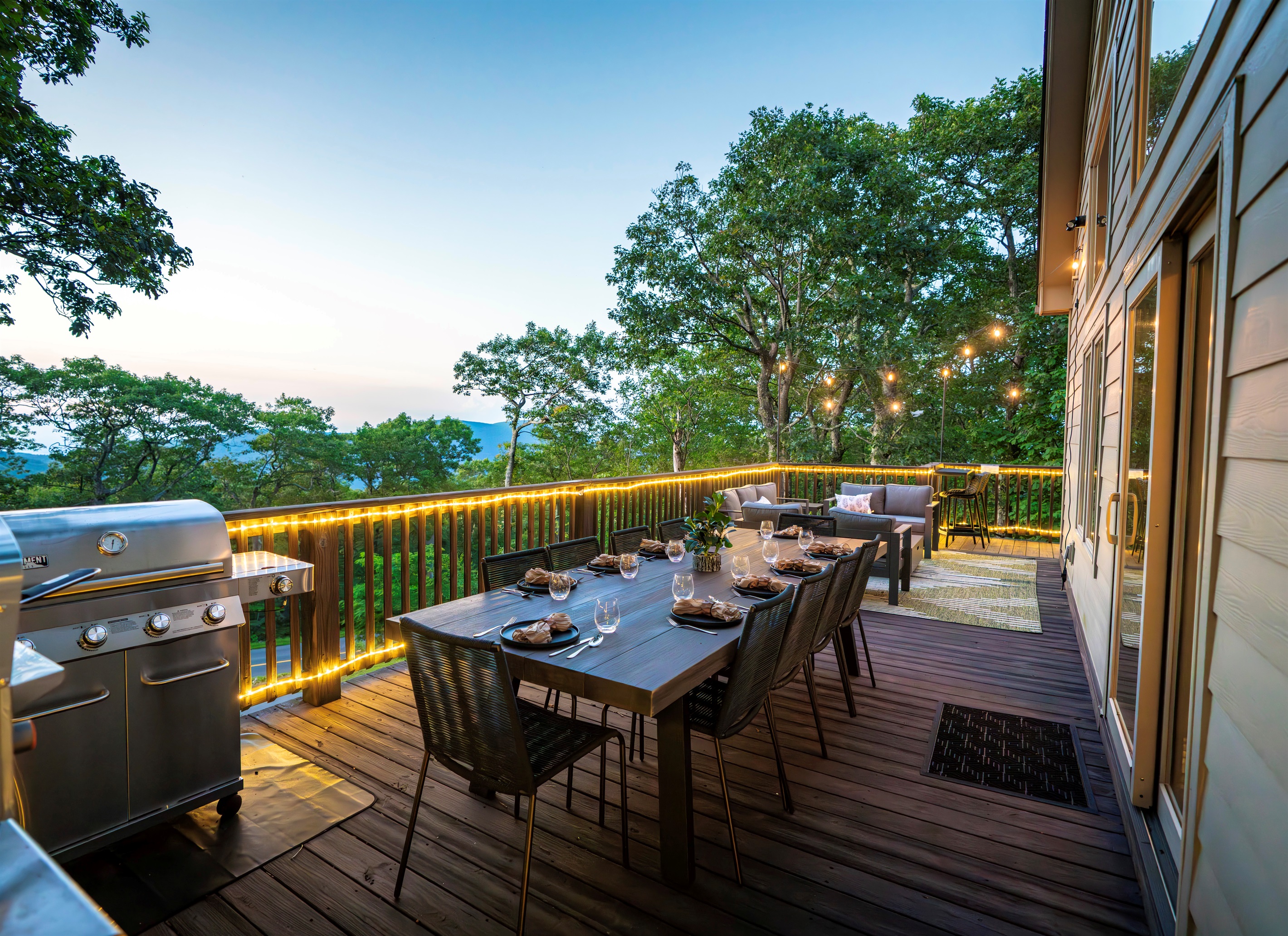 Twilight on the deck — mountains fading in the distance, wine glasses catching the glow of string lights, dinner sizzling on the grill. This is what gathering should feel like