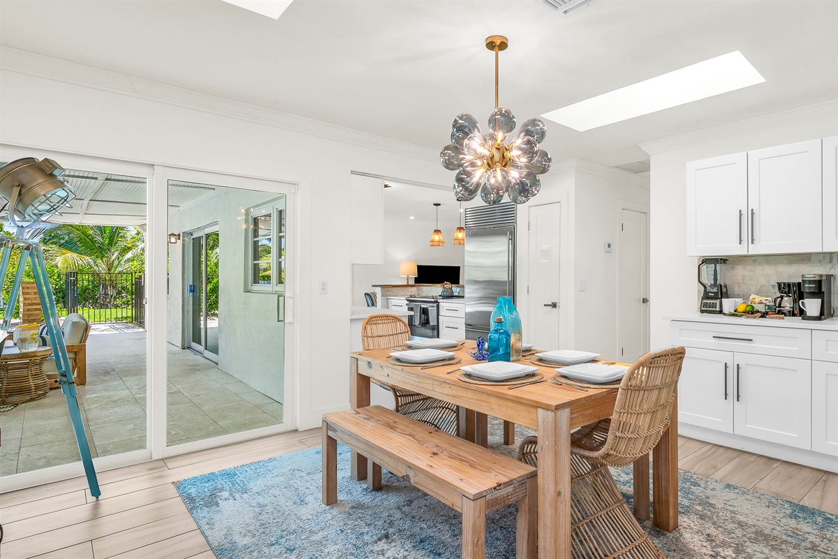 Gather around the rustic wood dining table with seating for six, accented by chic rattan chairs and a statement chandelier. Surrounded by natural light and stylish coastal décor, it’s the perfect space for enjoying meals or entertaining in style.