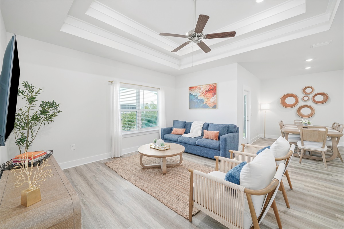 Modern and airy living room with ceiling fan, Smart TV, plenty of natural light and comfortable seating