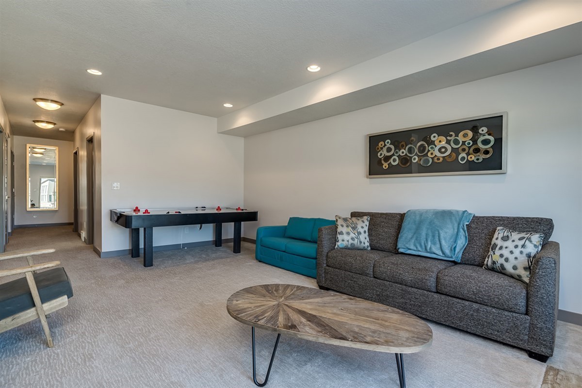 A spacious downstairs recreation room with comfortable seating and game space—ideal for entertaining or unwinding after a day outdoors.