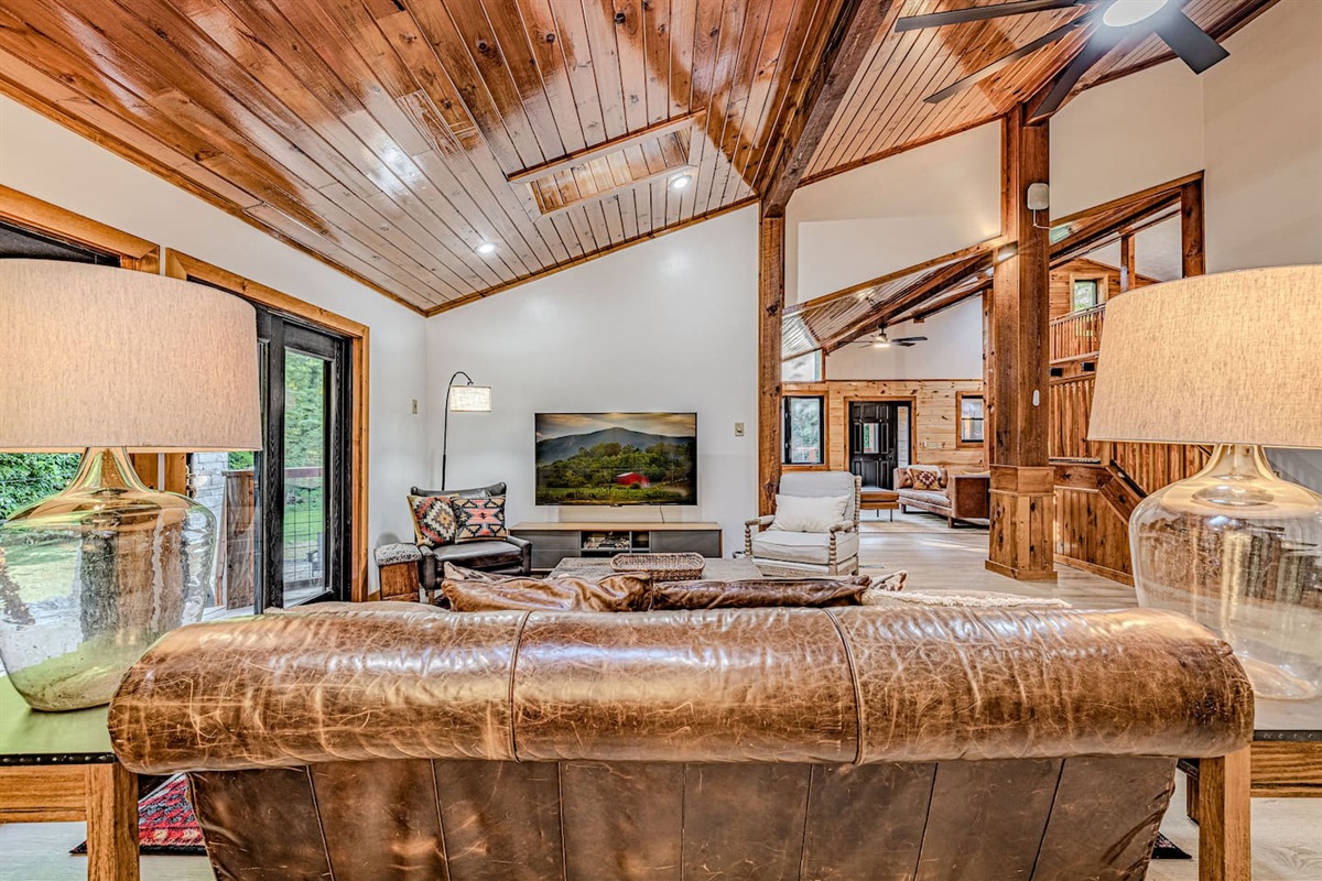 The light-filled main living room flows seamlessly to the expansive outdoor deck and connects to a second lounge, offering generous seating and a large TV for effortless gathering.