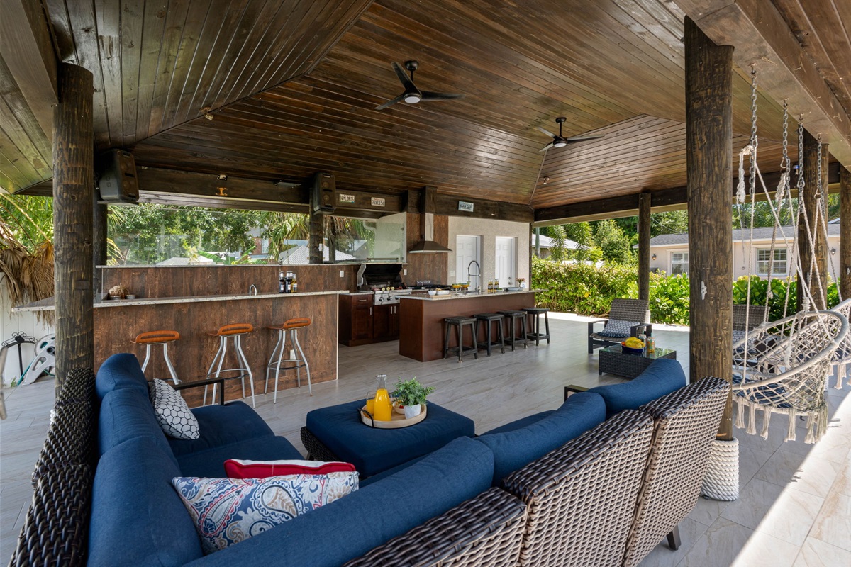 Enjoy serene water views from this beautifully landscaped backyard featuring swaying palm trees, vibrant flowers, and a spacious covered outdoor kitchen.