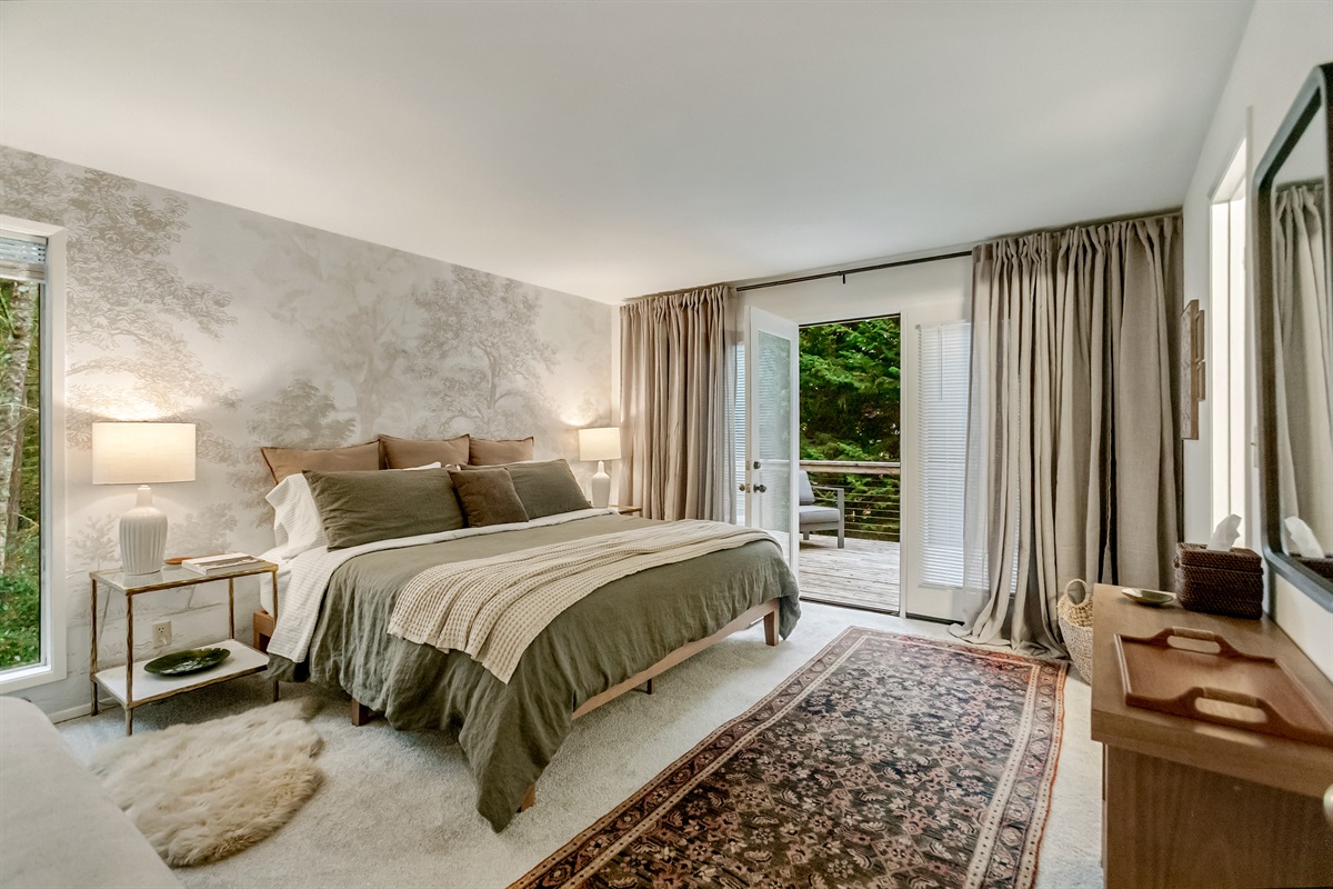 The primary suite upstairs has its own exterior entrance leading directly to the tree-lined deck.