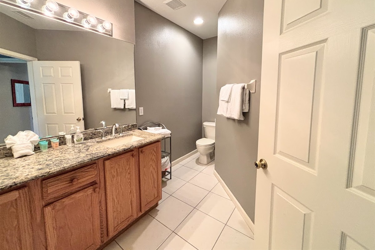 Spacious bathroom featuring a large vanity, granite countertop, tile flooring, and clean neutral finishes.