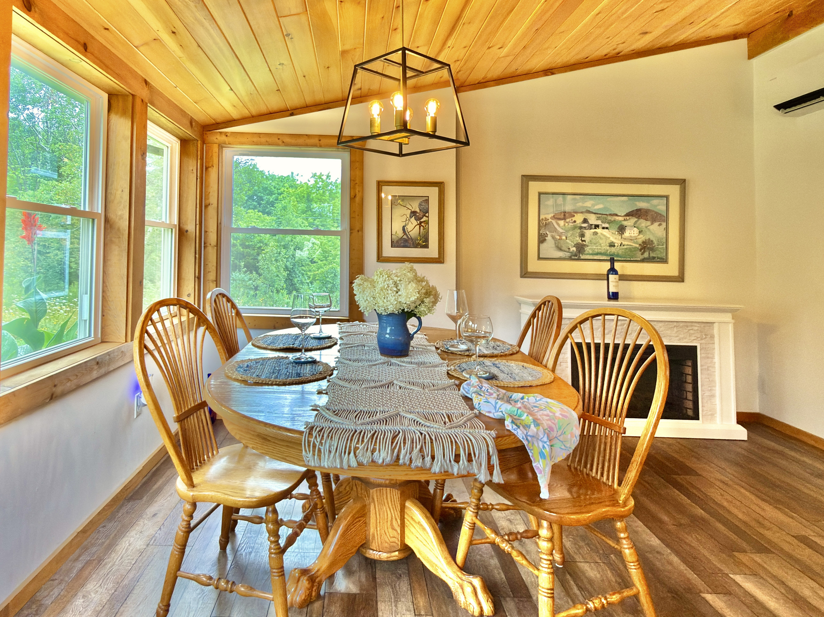 Our dining room features an Amish-crafted oak table and an electric fireplace, all framed by windows overlooking our 'hummingbird café' and hydrangeas. This space serves as our main entrance, providing a beautiful view of nature from the moment you arrive.