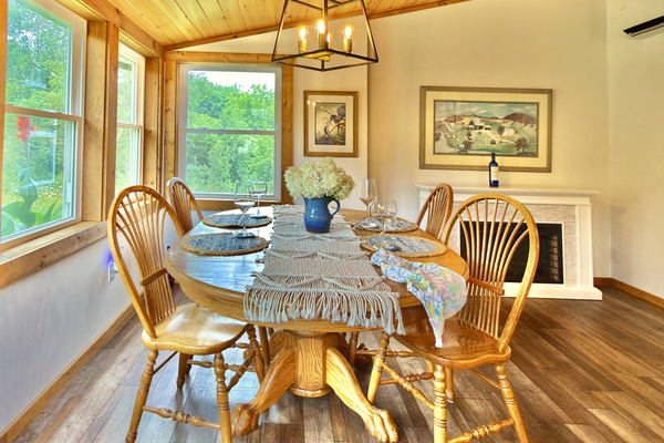 Our dining room features an Amish-crafted oak table and an electric fireplace, all framed by windows overlooking our 'hummingbird café' and hydrangeas. This space serves as our main entrance, providing a beautiful view of nature from the moment you arrive.