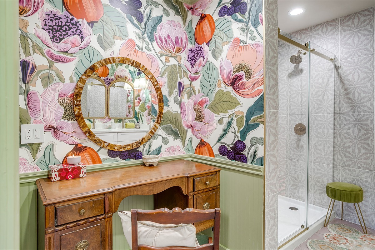 Primary bath with vintage sit-down vanity and glass barn door shower