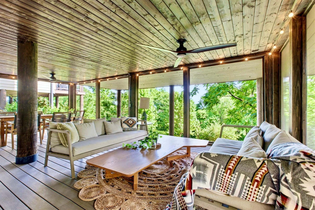 Shaded wraparound porch w/ wicker seating & treetop surroundings perfect for unwinding outdoors.
