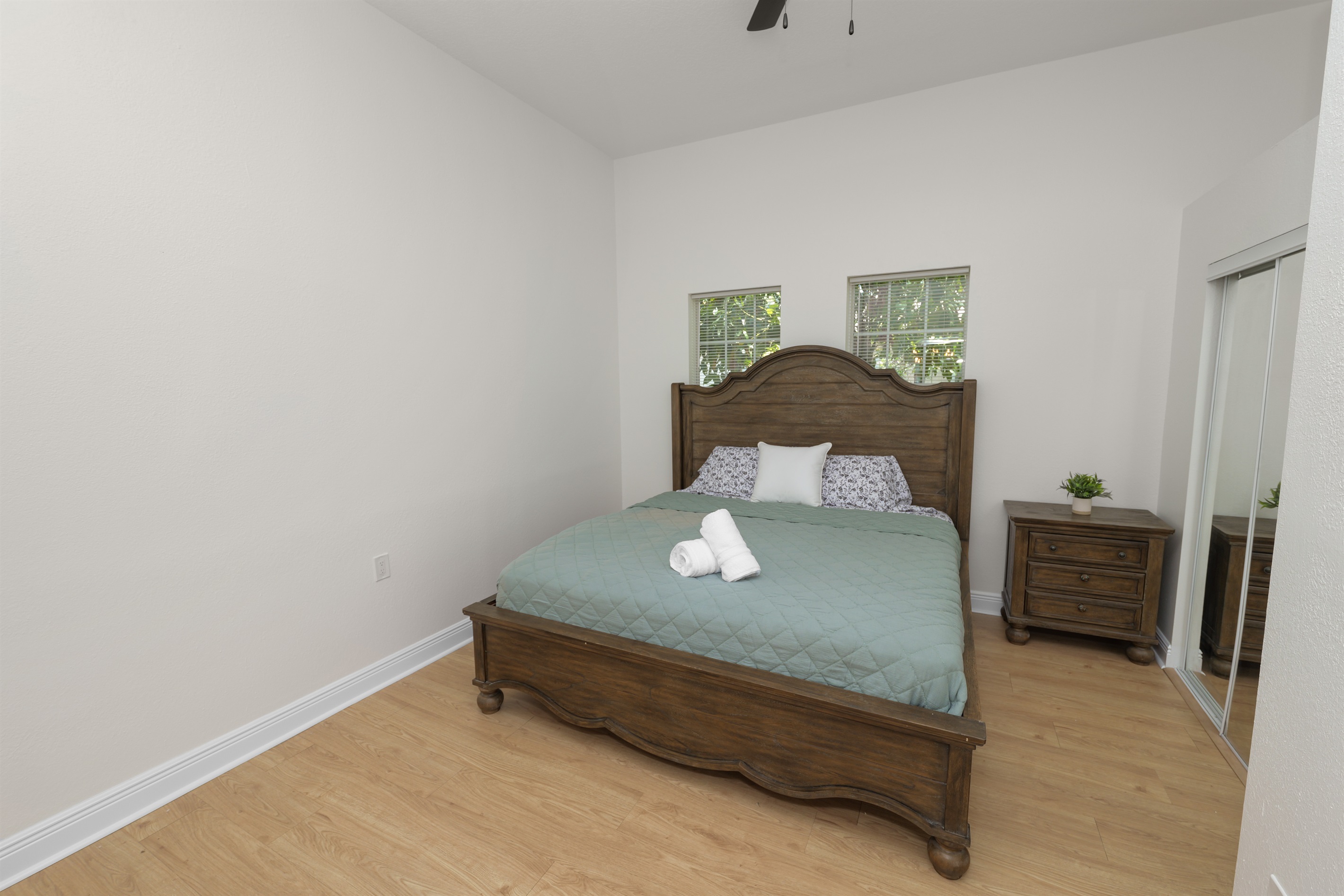 Rest easy in this serene primary suite featuring a king-size bed with a beautifully carved wooden frame and calming views of lush greenery.