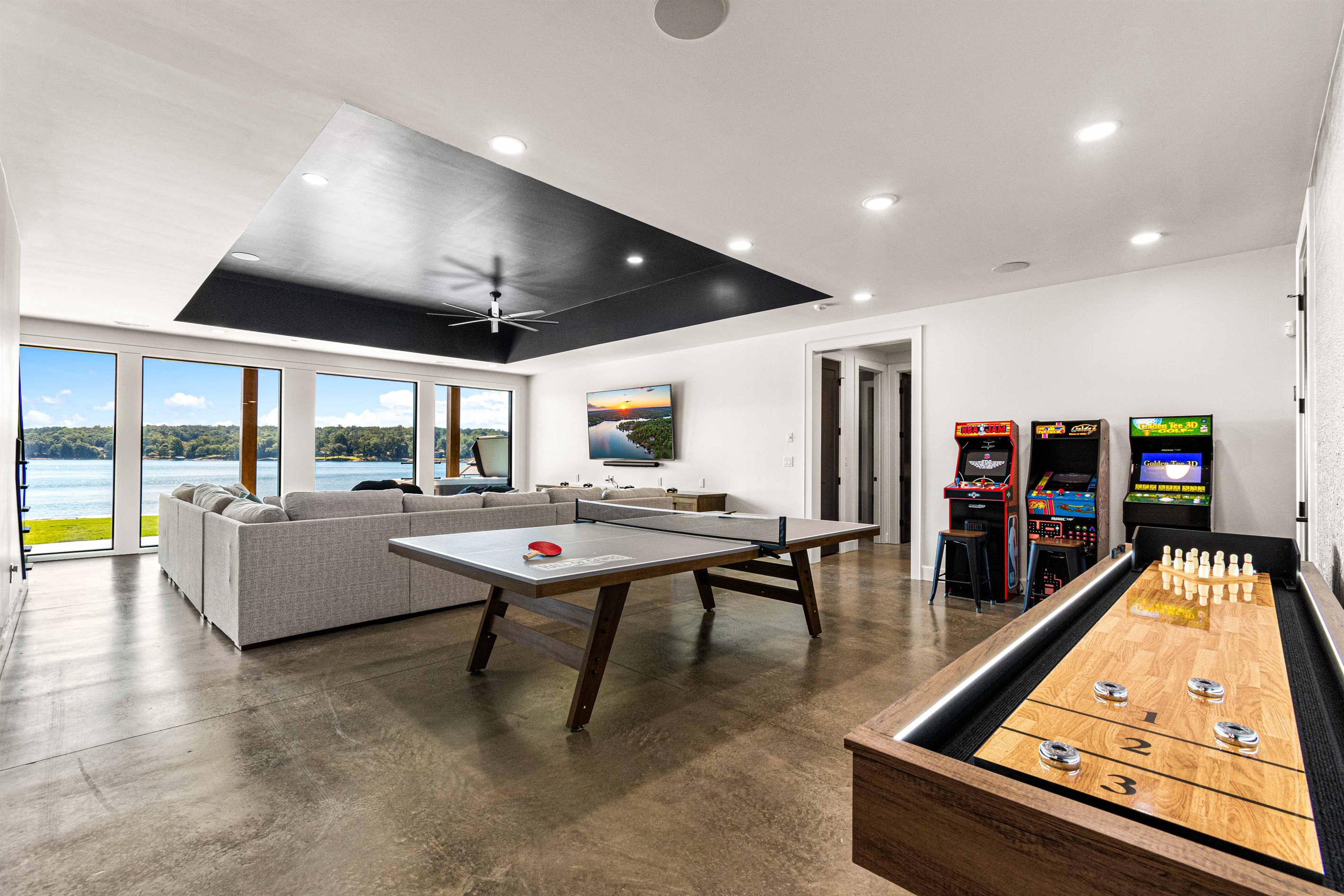 Basement Game Room equipped with ping pong table, shuffleboard and 70 inch TV and gaming console.