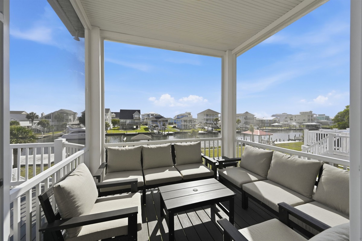 Relax on the screened-in balcony with comfortable seating and peaceful canal views