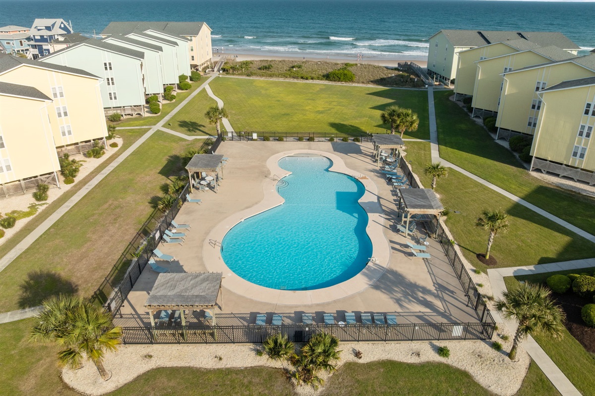 Resort-style pool centered between buildings with direct access to the beach beyond