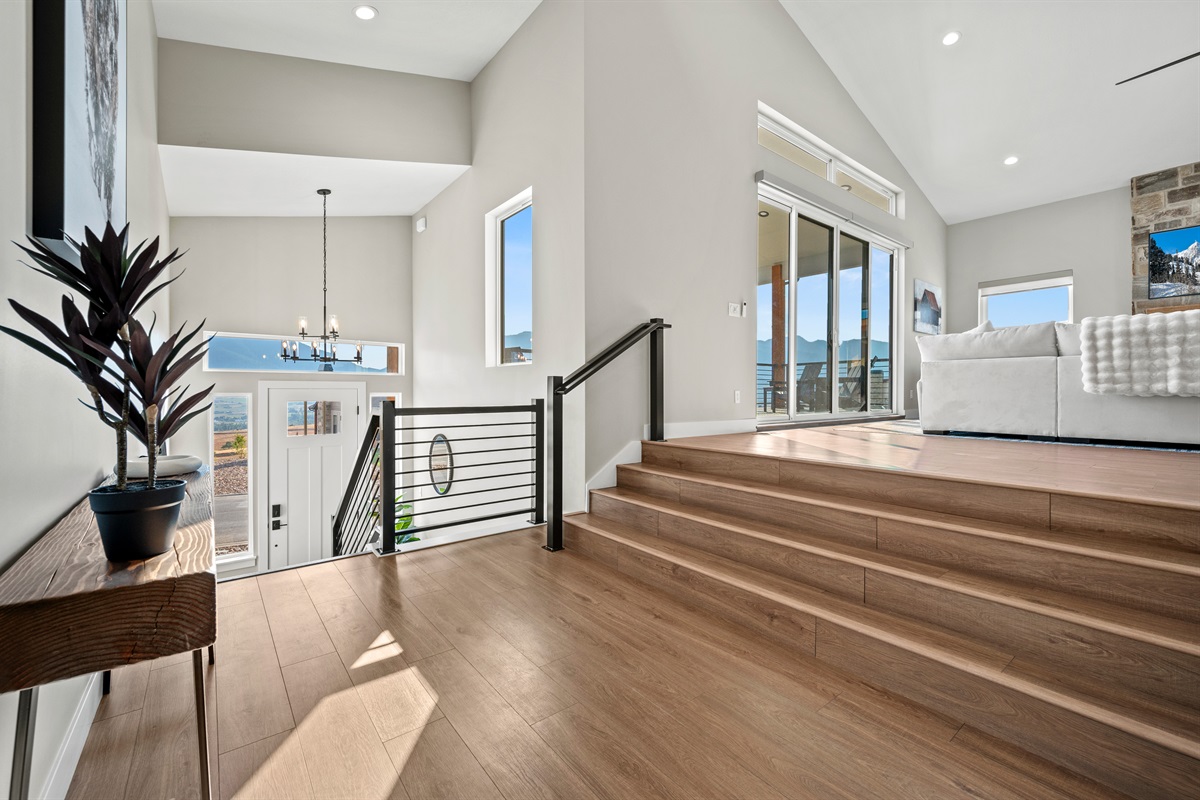 From the entry, ascend to the living room with cathedral ceilings and mountain views through expansive windows.