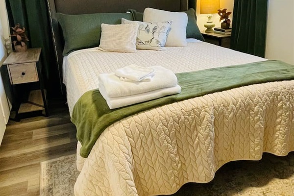 A serene queen bedroom featuring a TV and a calming nature-inspired theme with birds, blending soft patterns and layered elements for a restful retreat.