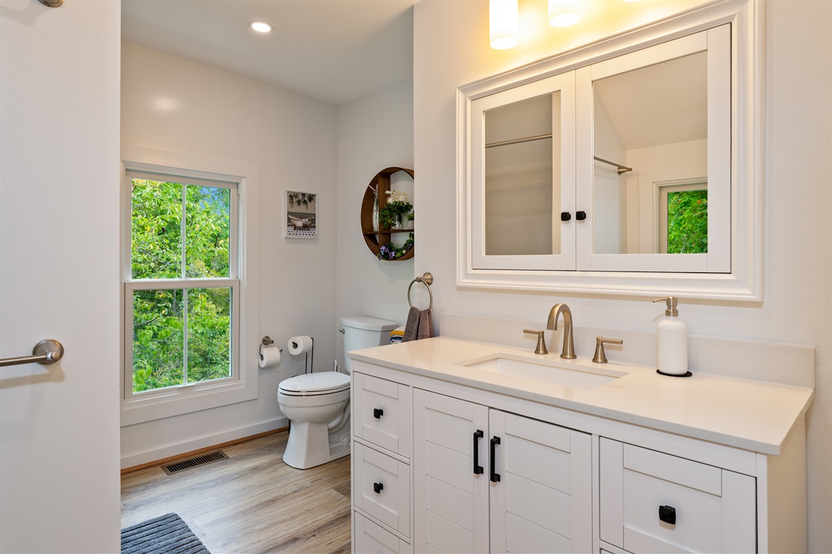 Bright and modern bathroom with a sleek vanity, stylish fixtures, and natural light pouring in from the window.