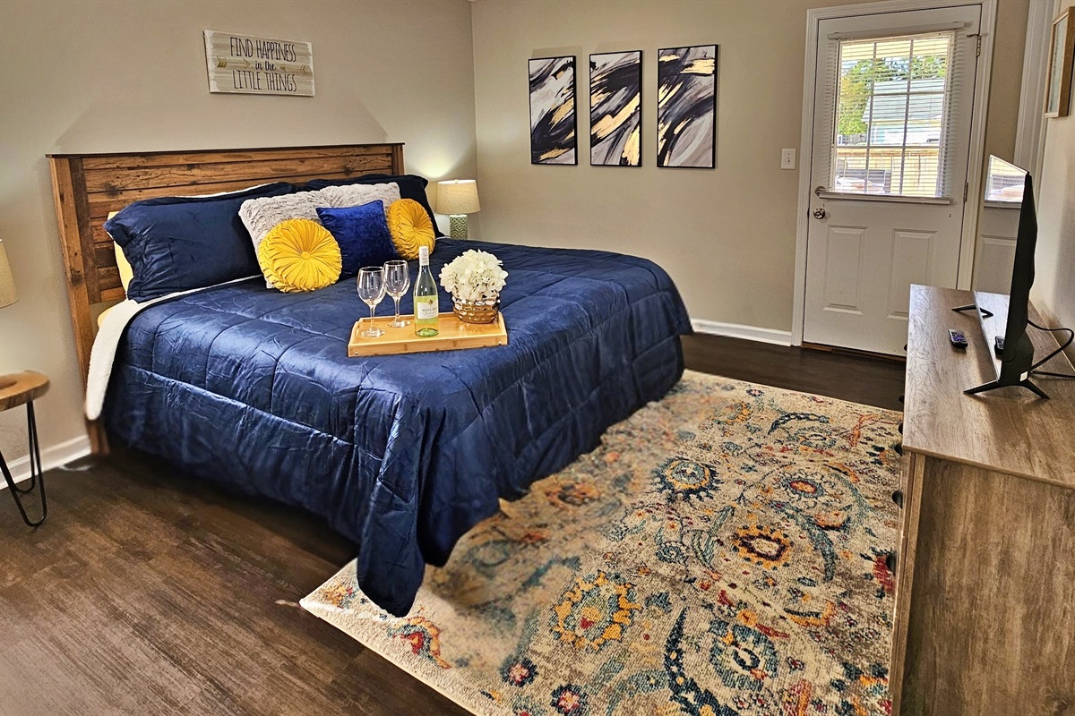 Relax in this farmhouse-style bedroom. There is a king bed along with a flat-screen smart TV. Step out the door to the back patio and fenced-in backyard.