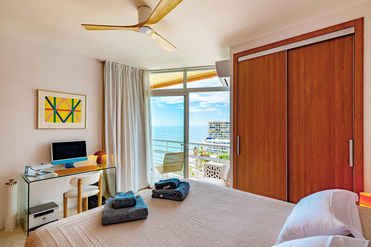 Main bedroom with artwork, natural light, and sea-view balcony access
