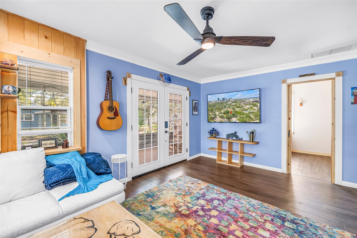 Comfortable living area with natural light, stylish wood accents, French doors, and a colorful rug that adds warmth and character to the space.
