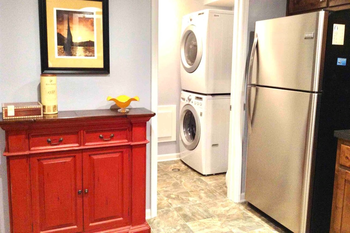 Stainless steel refrigerator with ice maker, with newer front load washer and dryer in laundry room. 
