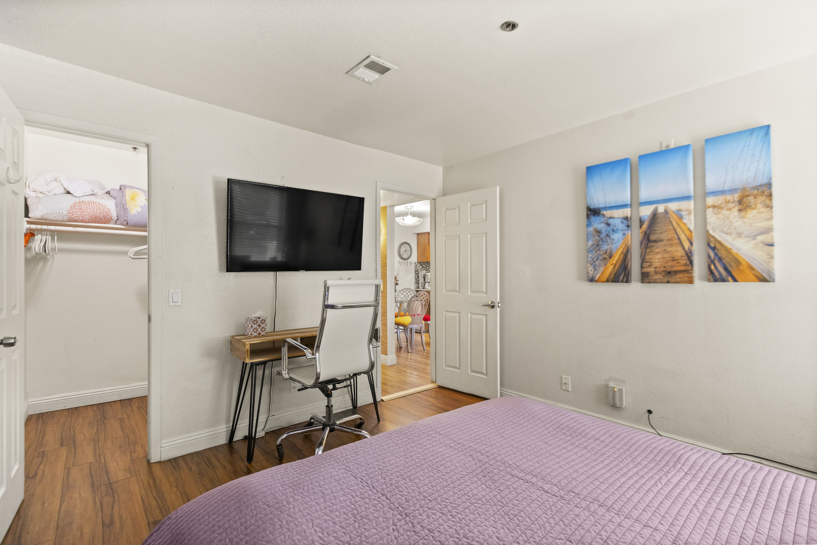 Bedroom 2 with a king bed, wall-mounted TV, desk workspace, and closet storage.
