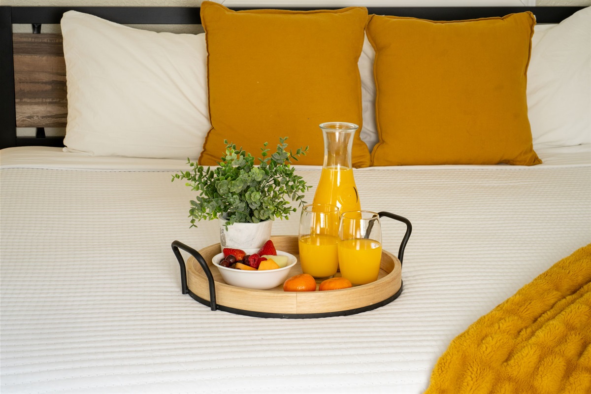 A cozy bed with mustard accents and a sleek black sofa create a stylish retreat with direct access to the outdoors.