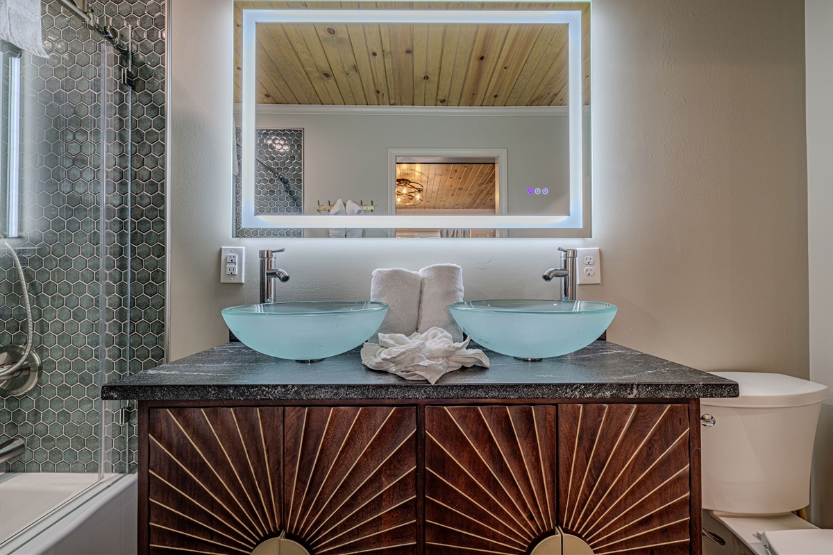 This sophisticated bathroom features unique frosted glass sinks and a designer vanity that perfectly captures the mid-mod mountain aesthetic.