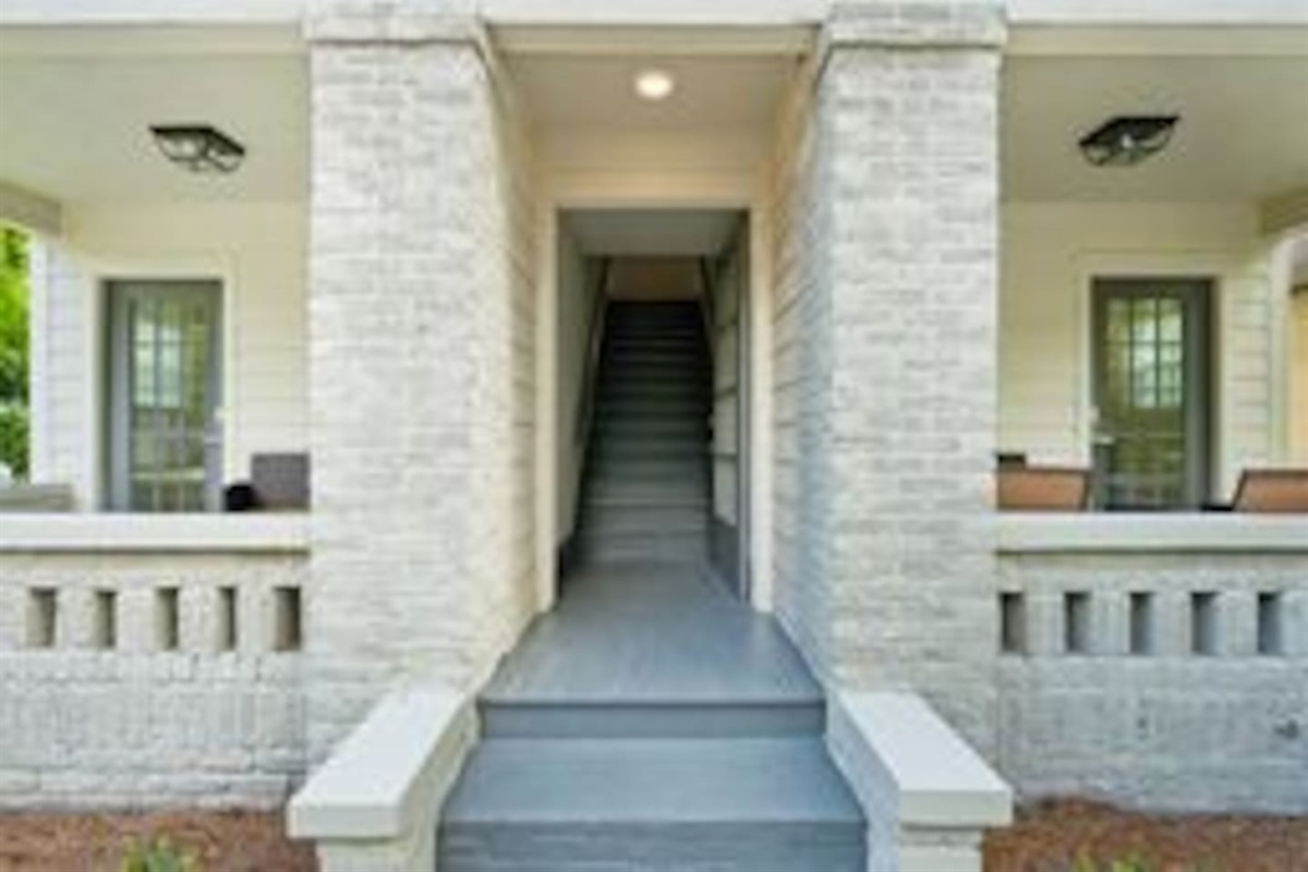 The middle doorway leads to a flight of stairs. The stairs lead to Units 3 & 4. The welcoming entryway to the building features a traditional porch that adds a touch of Southern charm.