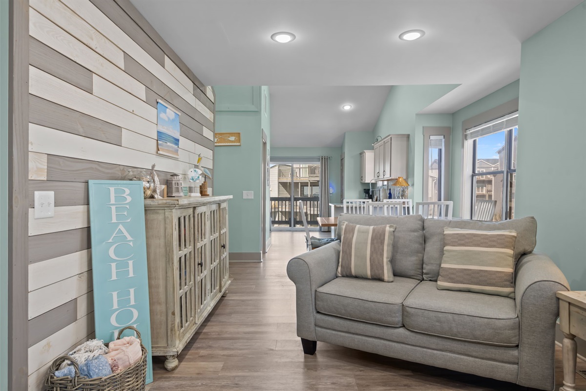 Stylish coastal living space with comfortable seating, charming beach d&eacute;cor, and an easy flow into the dining area and kitchen