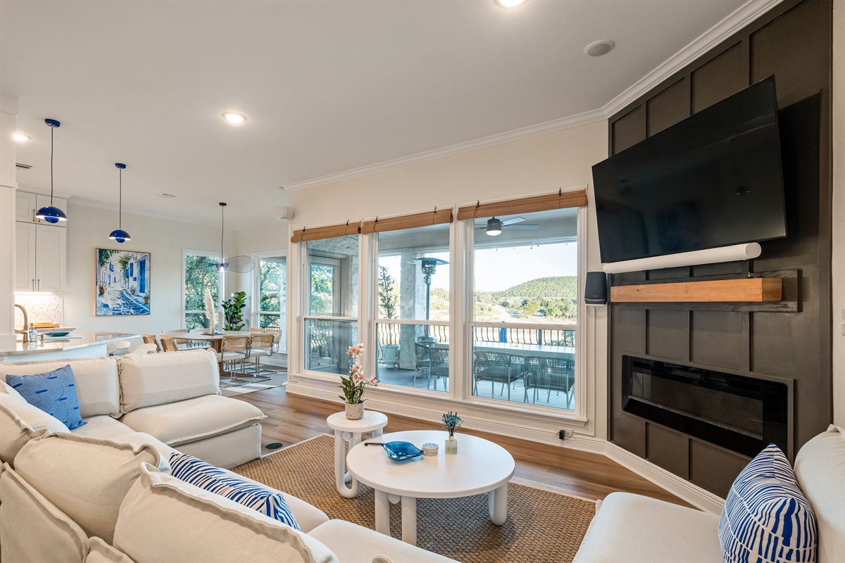 Stunning lakeview living area featuring floor-to-ceiling windows, cozy seating, and a large Smart TV.