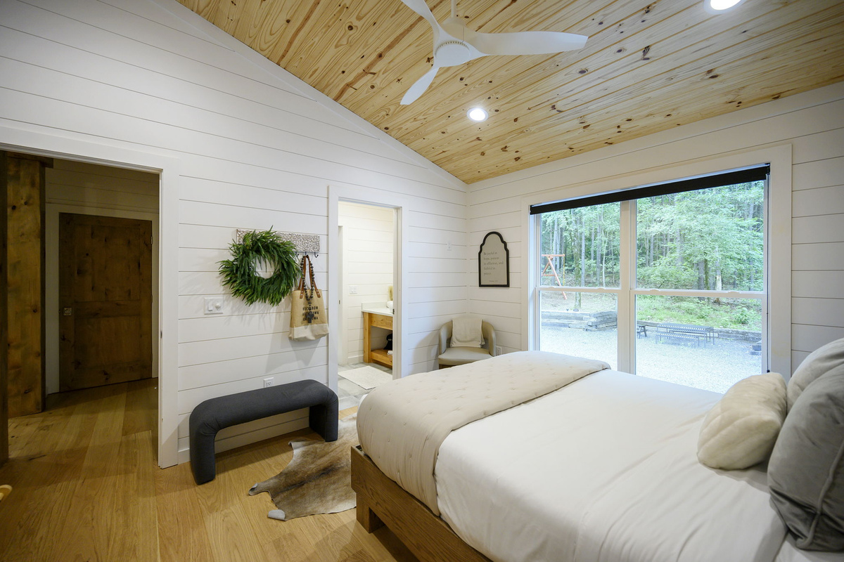 A beautifully appointed queen bedroom featuring luxury design, high-end linens, and peaceful forest views.
