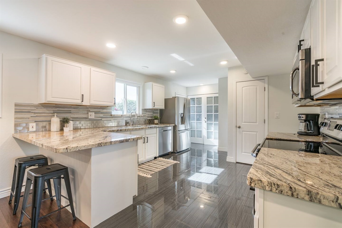 Kitchen is adjacent to the dining room. It's well-stocked and features a breakfast bar