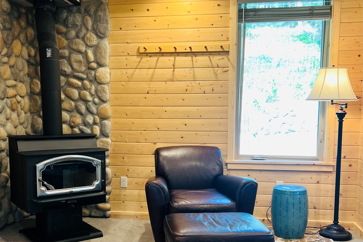 Rich leather armchair next to wood stove offers the perfect spot for a glass of wine or a nice book, A duraflame log is provided for your stay. Please do not cut wood in the house or on the patio