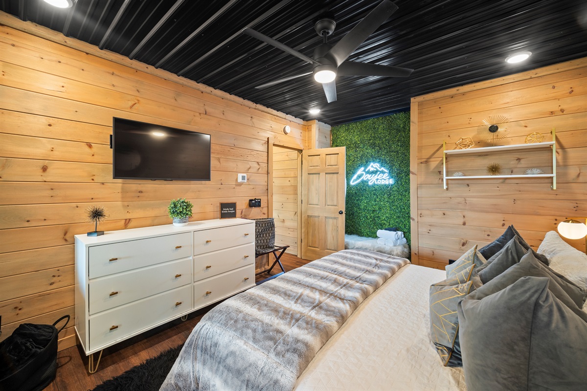 This contemporary king bedroom features cozy decor, soft lighting, and a greenery wall that adds that Boujee touch.