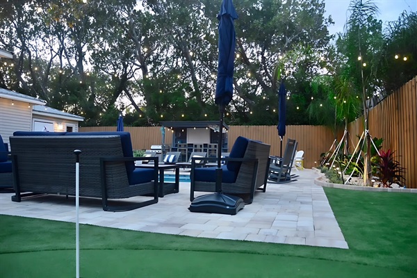 Daytime view of the expanded patio, new seating, upgraded landscaping, putting green and lighting