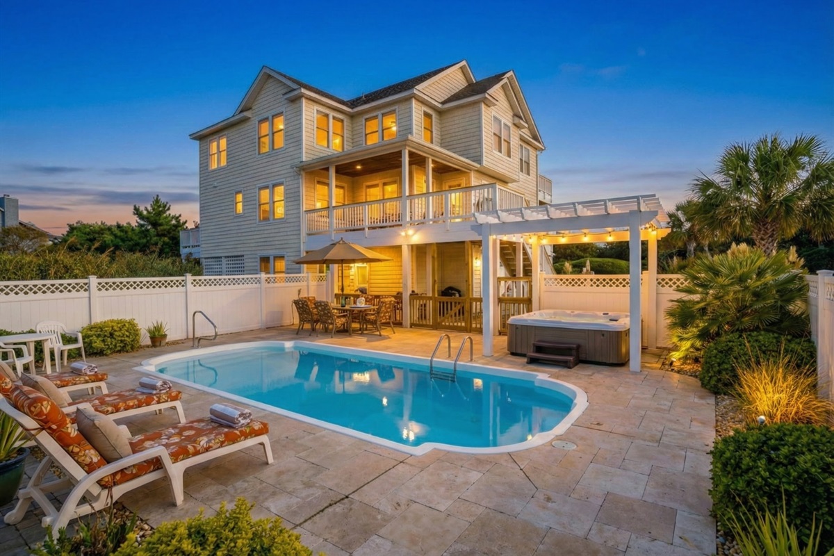 A view of the home's rear exterior showcasing the multi-level decks and the sparkling private pool area surrounded by a white privacy fence.