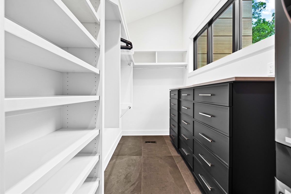 Enjoy a well-organized space with this spacious walk-in closet, featuring modern black cabinetry and efficient shelving.