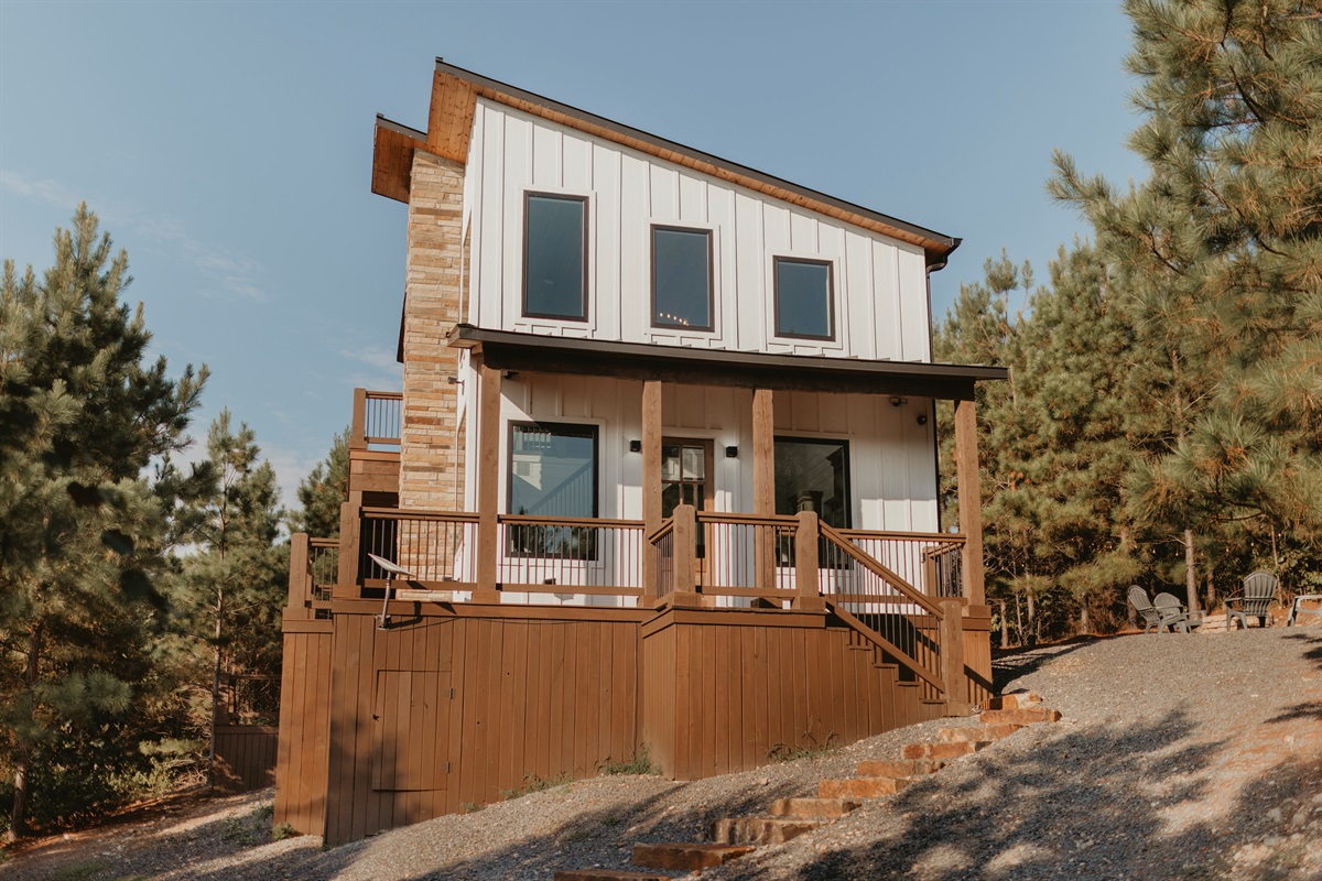 A striking cabin exterior with modern lines, stone accents, and tall windows. Elevated among the pines, it offers both style and seclusion for a peaceful mountain getaway.