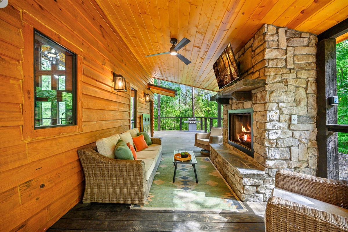 Chill out on the covered patio featuring a stone fireplace, wall-mounted TV, and comfy seating. Great for game day or a peaceful retreat.