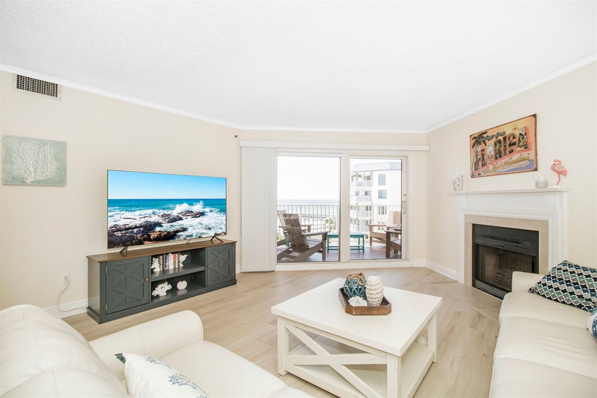 Living room with fireplace, open to the dining and kitchen area with pool and gulf views. 