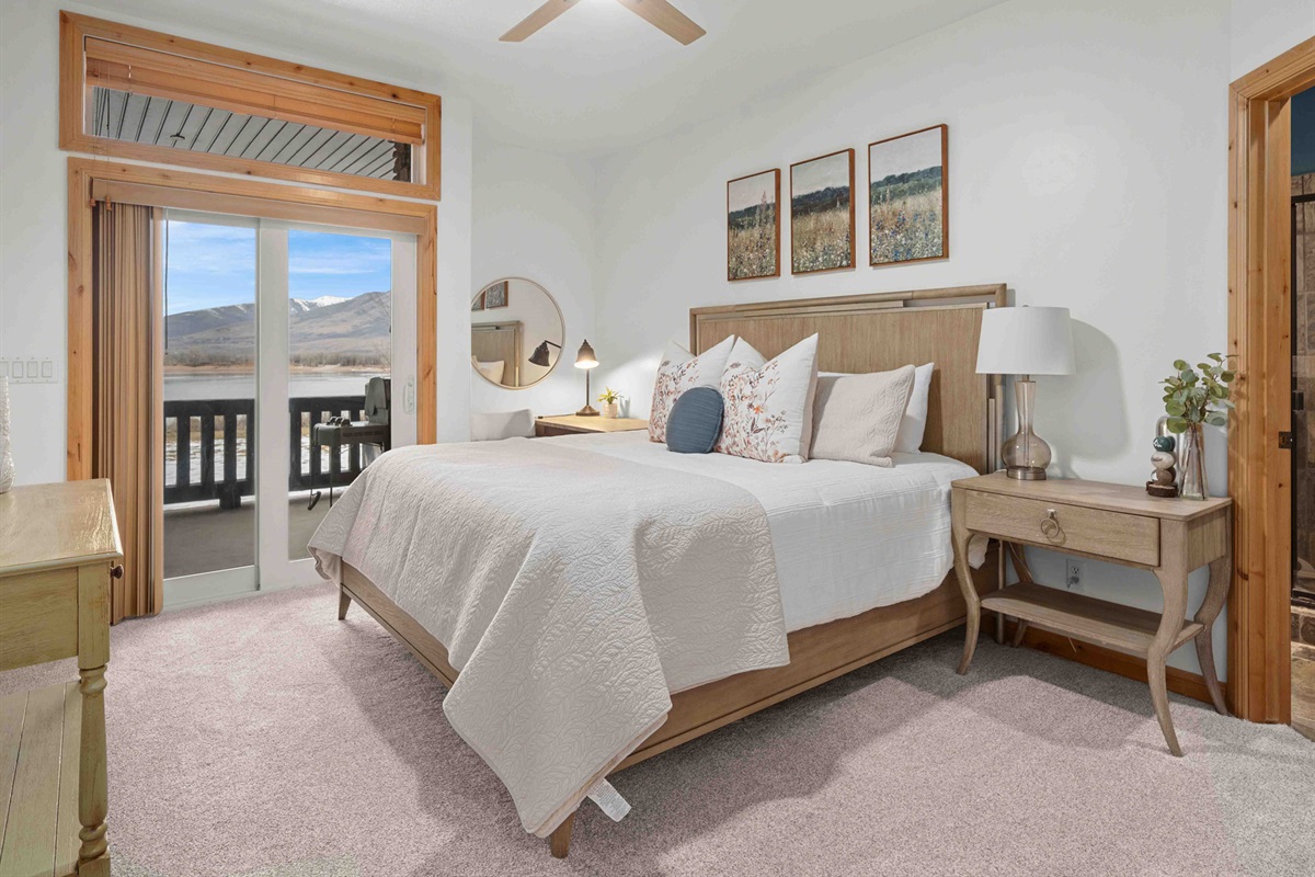 Bright and serene bedroom with a plush bed and direct access to a private balcony with lake and mountain views.
