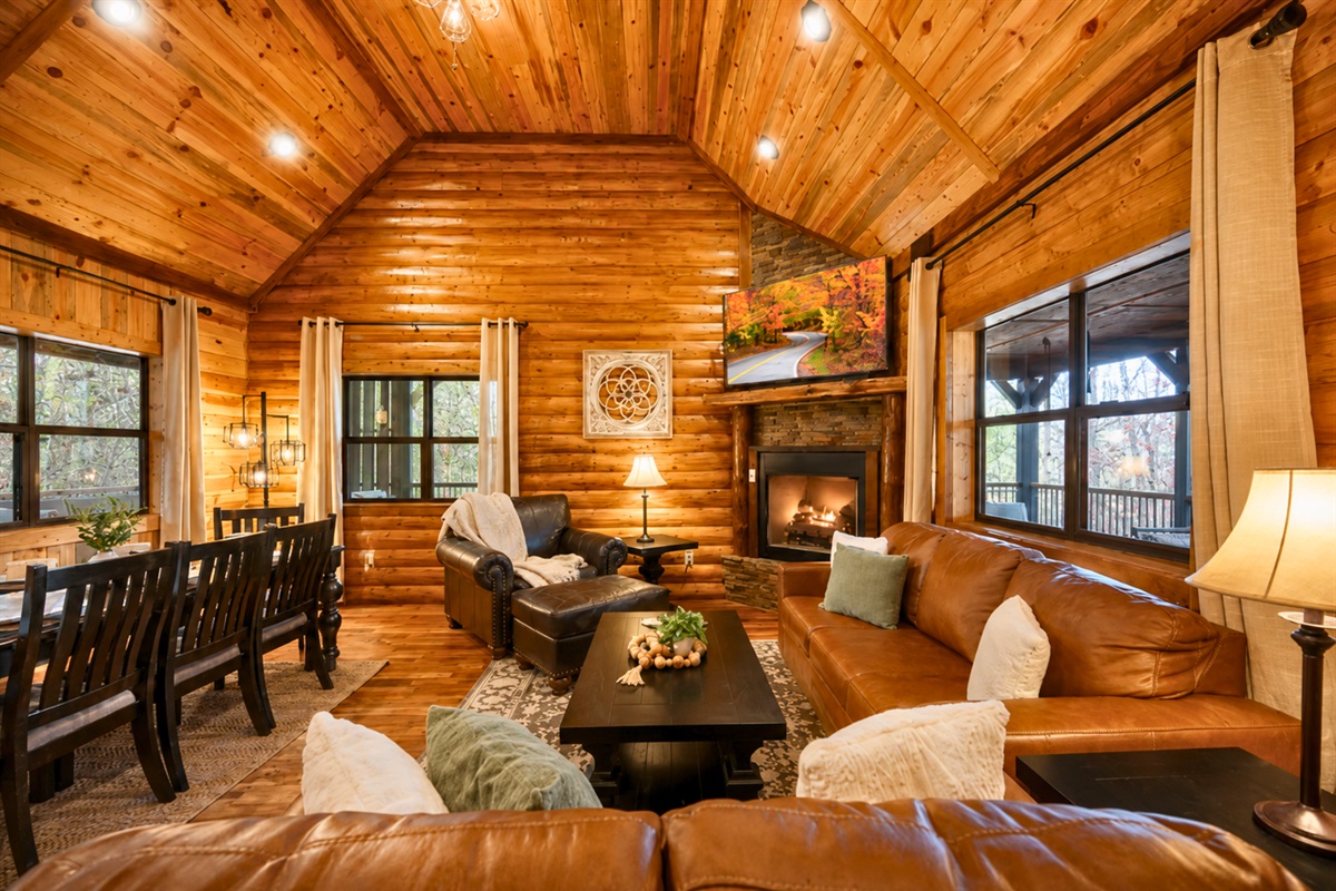 Stepping inside, you&rsquo;re welcomed by soaring wood ceilings, comfortable seating, and a stone fireplace that instantly makes the cabin feel warm and inviting.