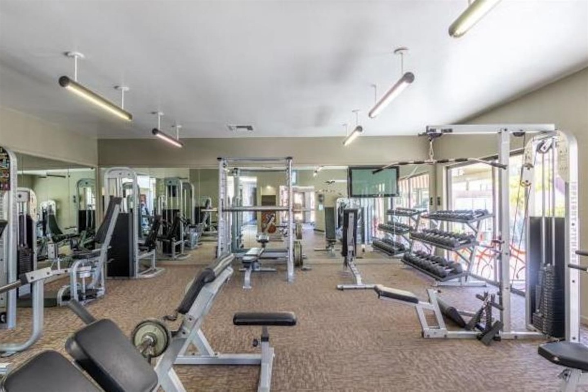 Shared gym with strength equipment, dumbbells, benches, and cardio machines for guest use.